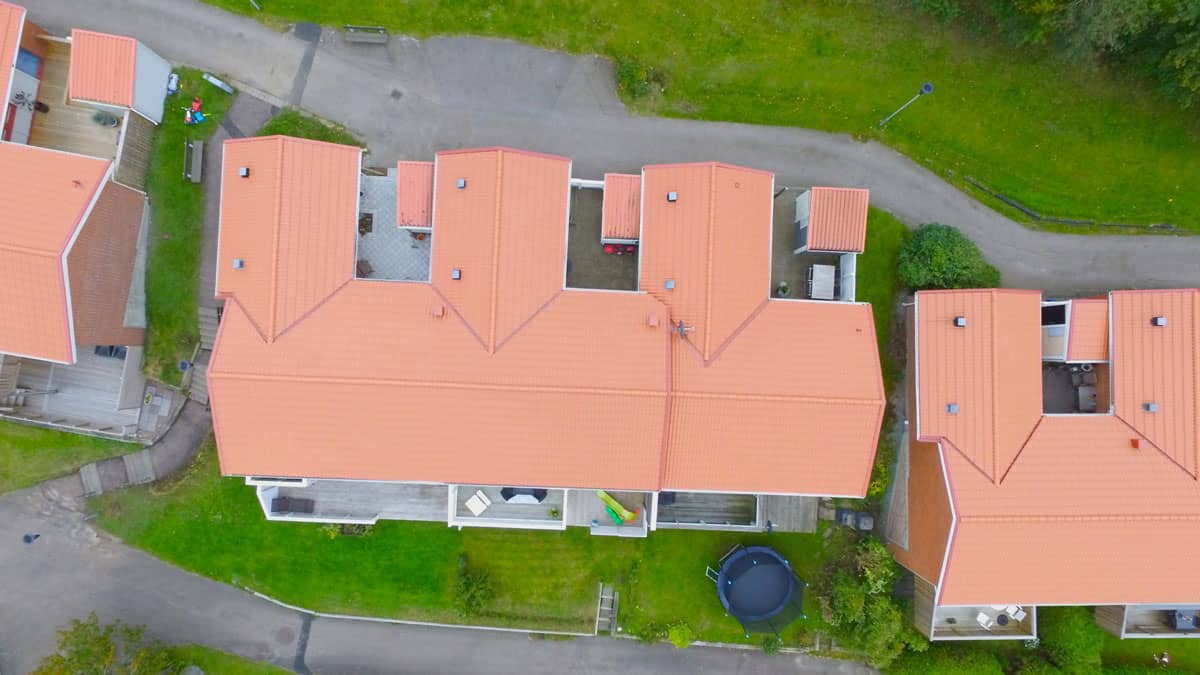 Drönarvy över omlagda radhustak med röda takpannor i Kungälv